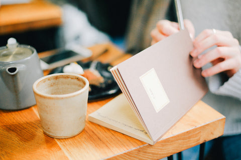 Person writing in a journal at a coffee shop