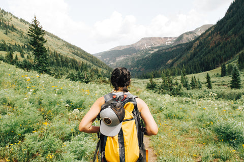 Person hiking in the mountains with yellow backpack on