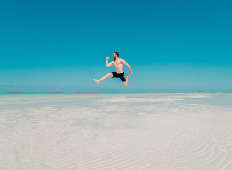 Man jumping high on beach sand