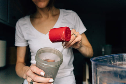 Woman putting protein into a bottle