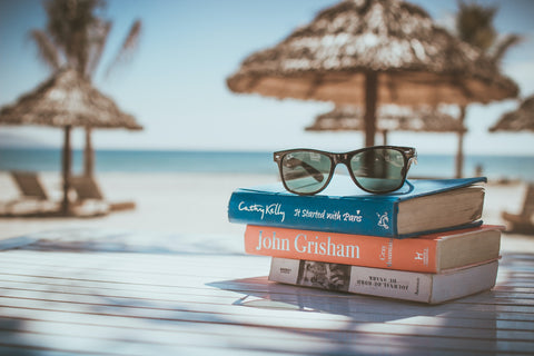 Sunglasses on stack of books at tropical location