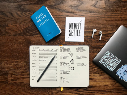 Desk flatlay with notebook, planner, and laptop