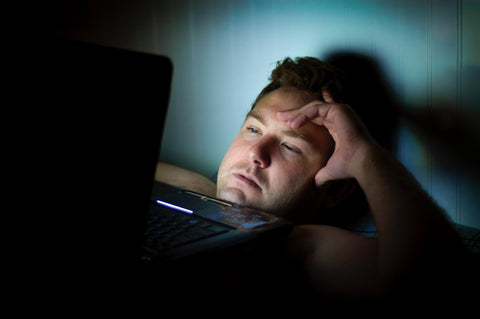 Man in bed with laptop, for better sleep don't use technology before bed