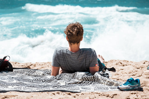 Man sitting on the beach looking out over the ocean