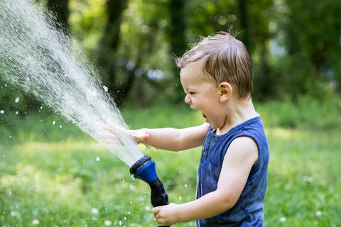 Happy child playing with water hose
