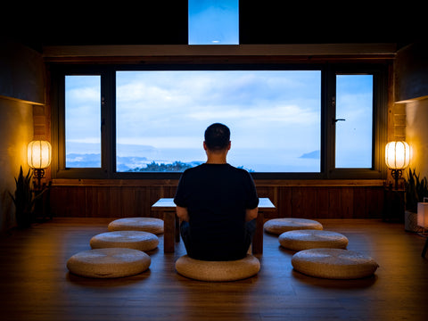 Man sitting on a yoga pillow in a room