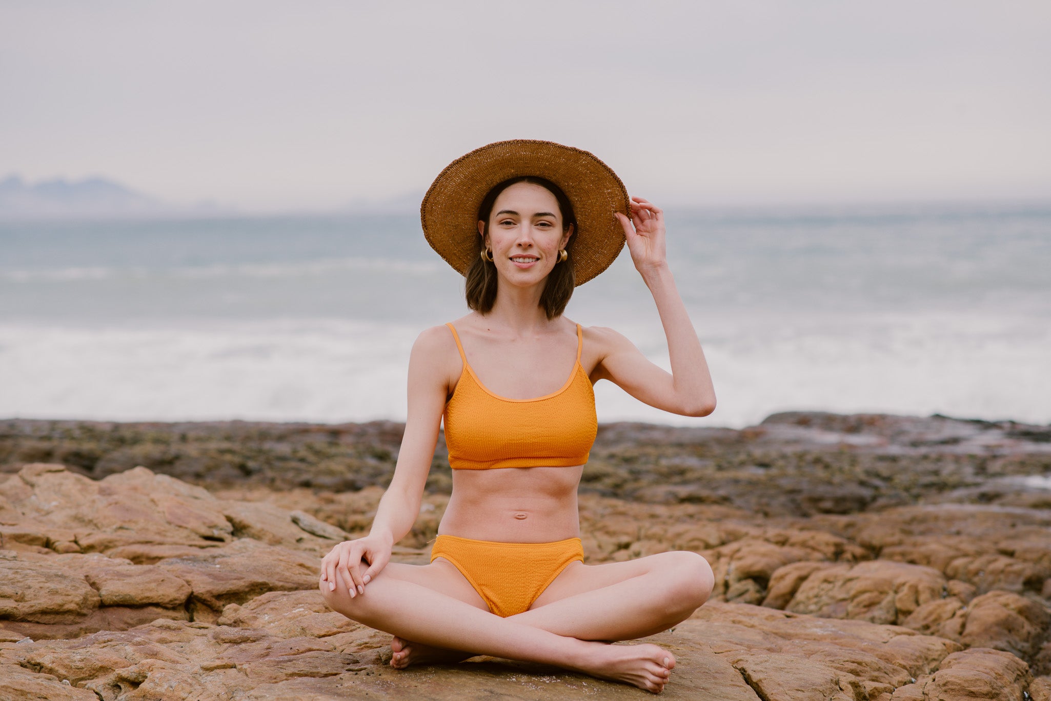 Lady sitting on rocks near the beach