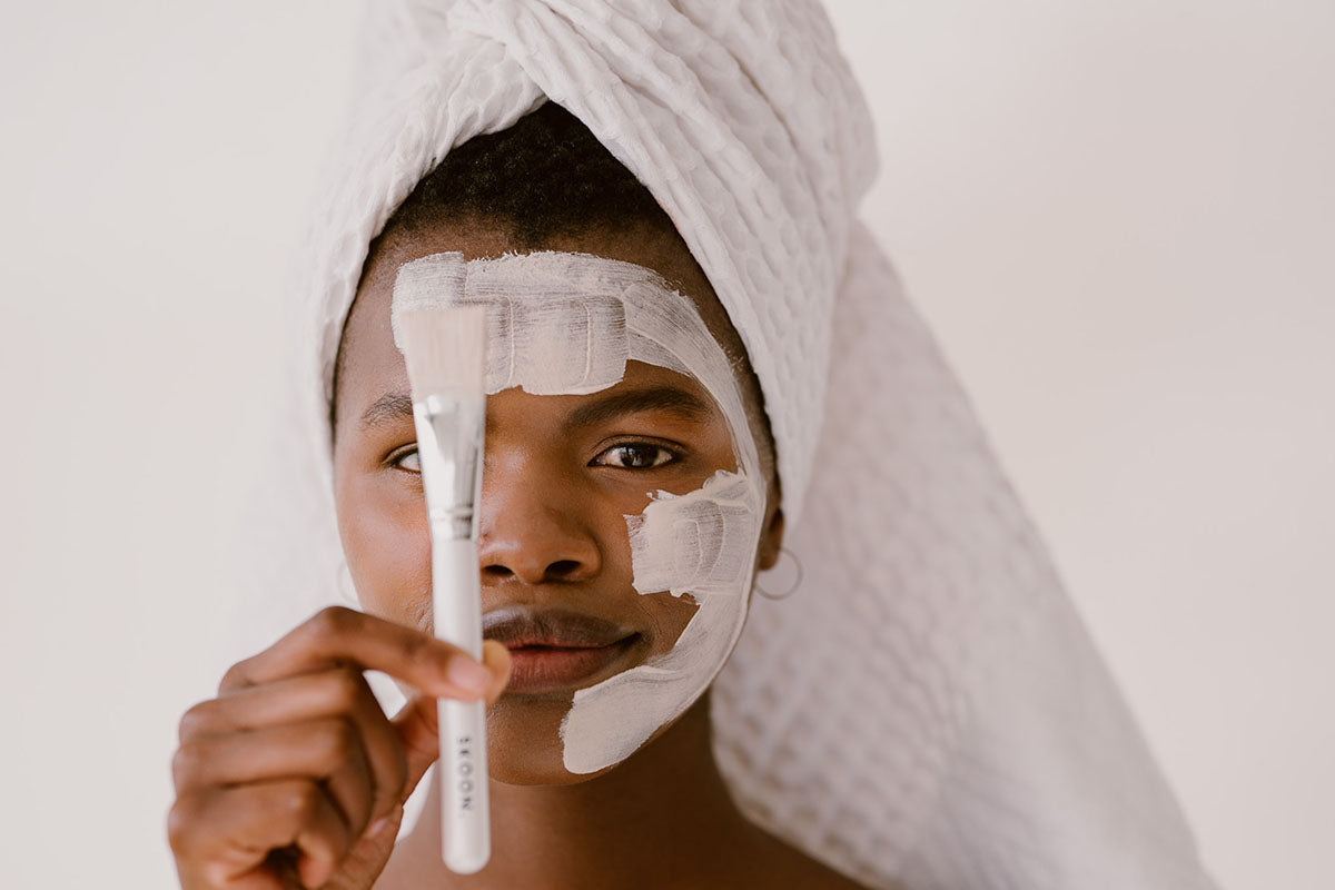 Woman holding brush with product applied to face