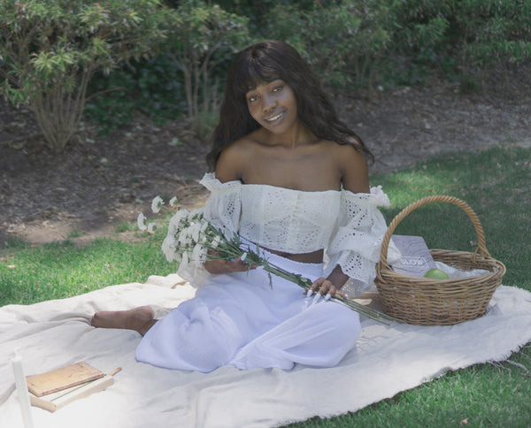 Ayune hair - Ethical hair extensions (Black woman sitting in a garden smiling)