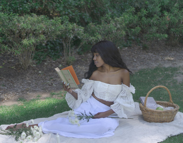 Ayune hair - Ethical hair extensions (Black woman sitting in a garden reading a book)