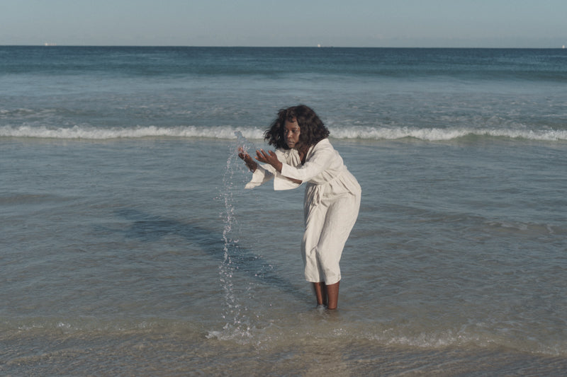 Black woman splashing water in the ocean.