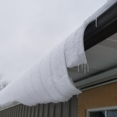snow curling off the edge of the barn roof