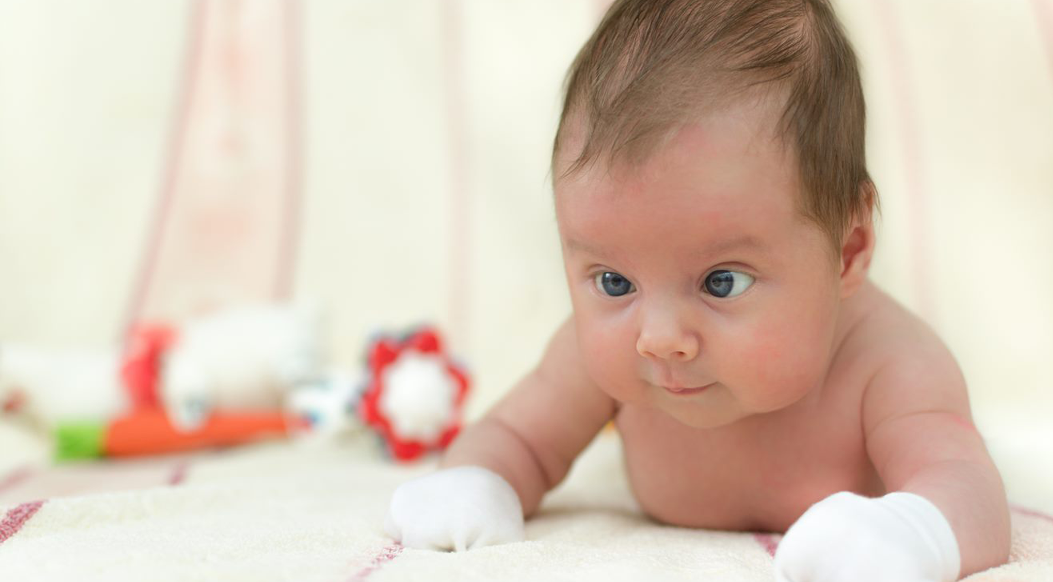 Baby lying down on stomach with crossed eyes