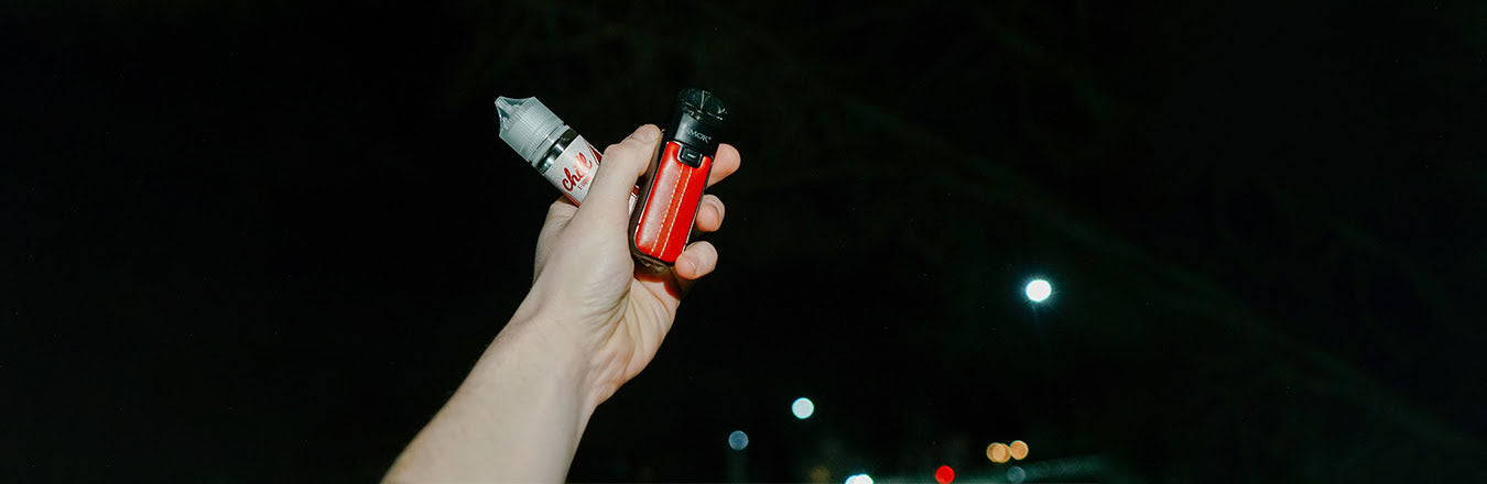 Hand holding SMOK Nord 50W device and e-liquid refill container