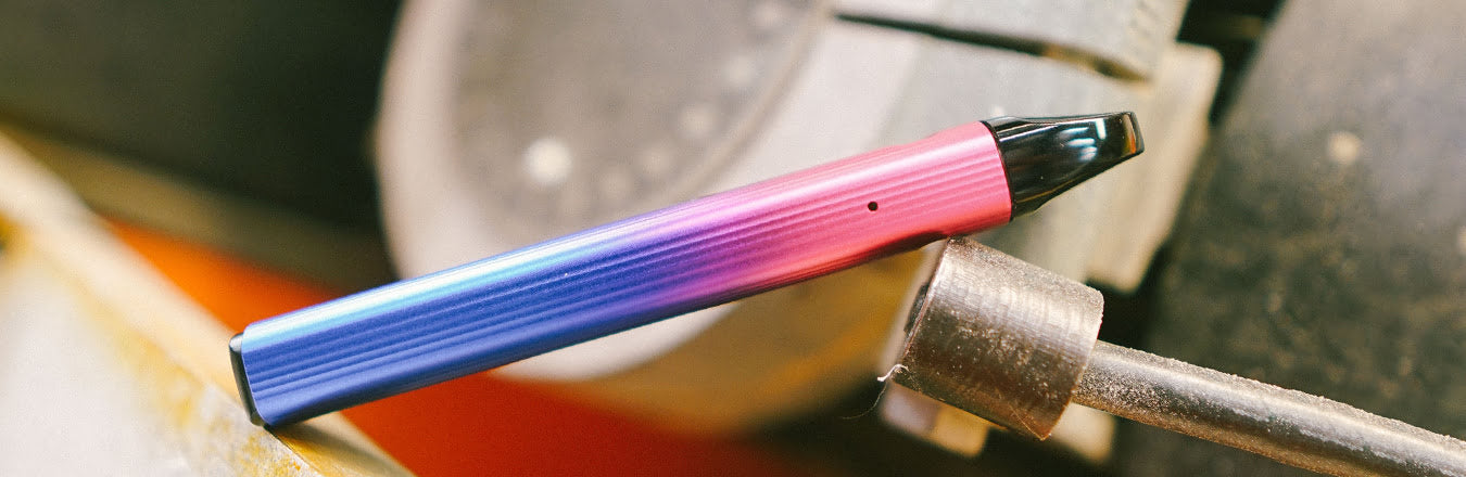 Side view of UWell Caliburn G2 in Gradient colour scheme lying diagonally on metal surface