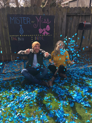 Couple posed in front of a mister or miss board with tally marks and the couple surrounded by blue confetti.
