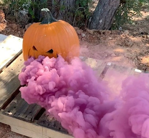 Picture of a carved pumpkin with pink smoke coming out of it.