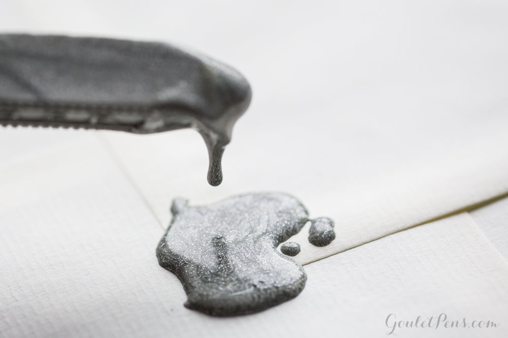 A stick of silver sealing wax dripping onto paper