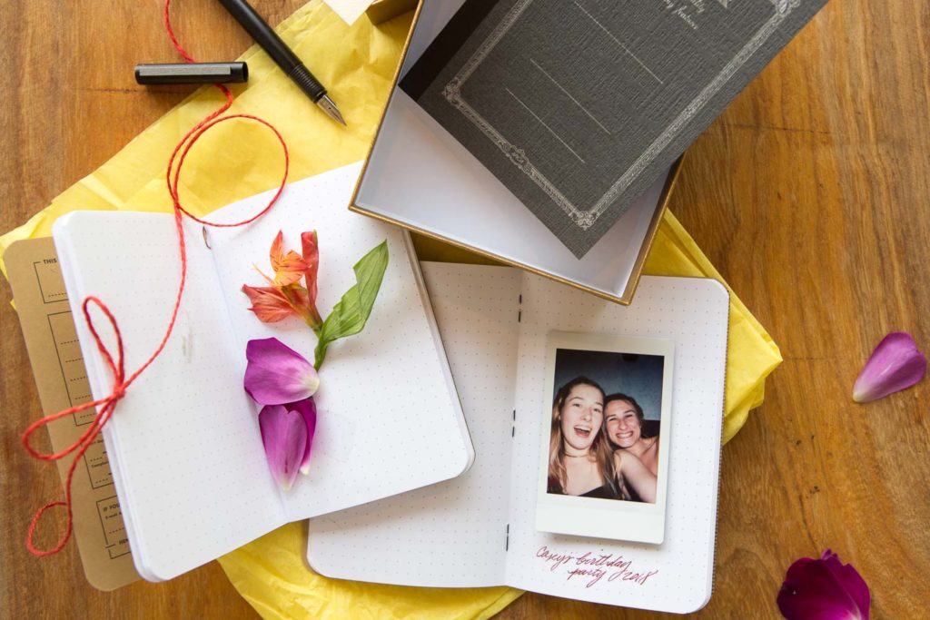 Some flower petals in a small notebook with a piece of string on a desk