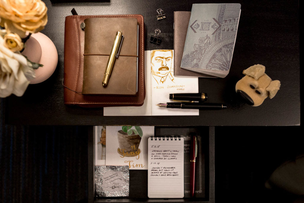  Travelers Fountain pen and notebook on a desk with a vase of flowers