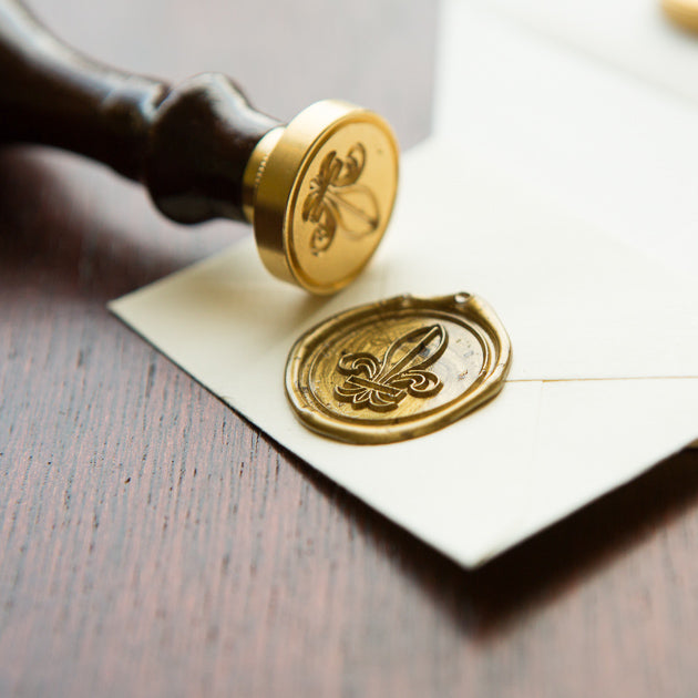A gold colored wax seal on a piece of paper