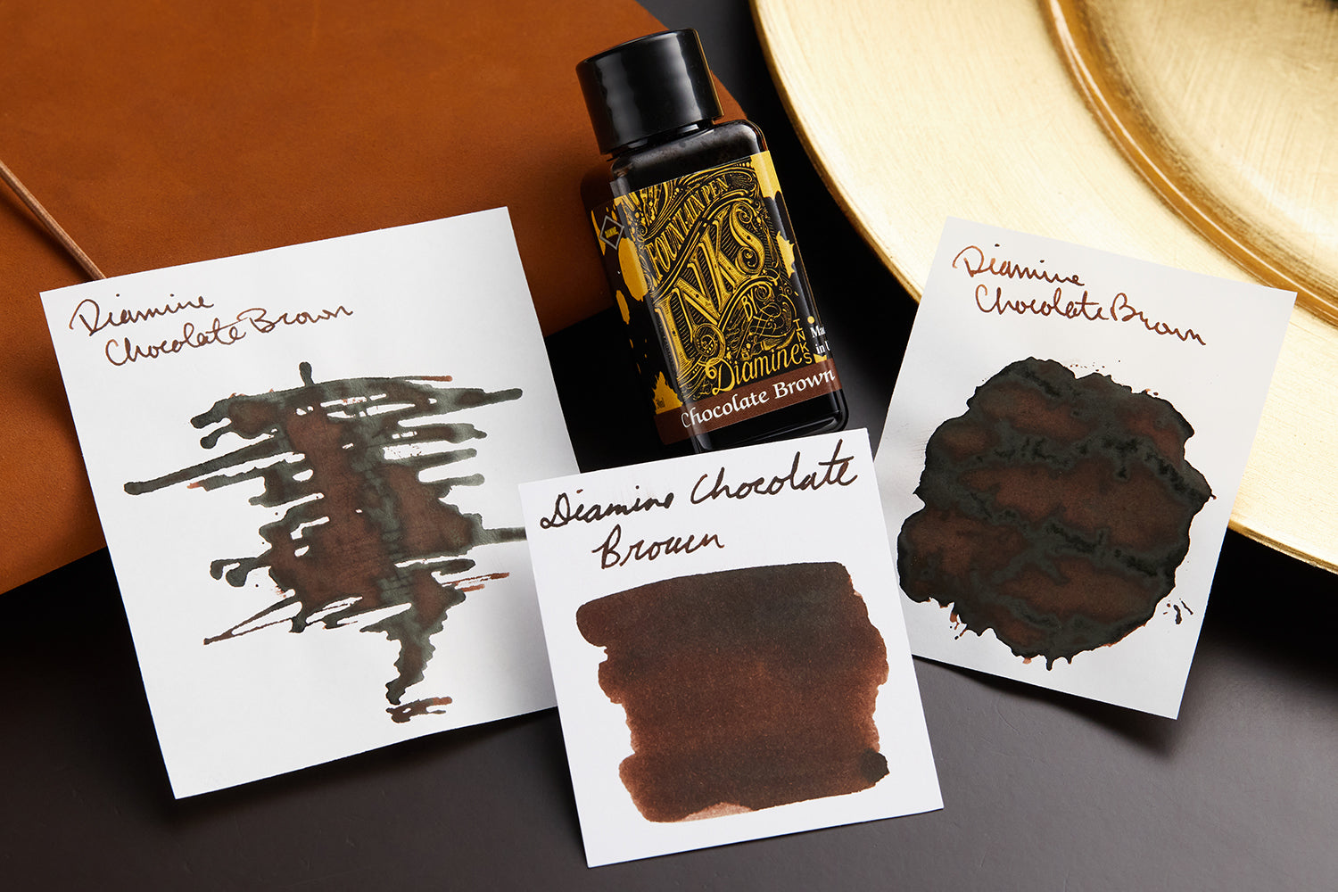 Diamine Chocolate Brown Fountain Pen Ink with ink swab, swatches, writing sample, and bottle on leather desk blotter background.