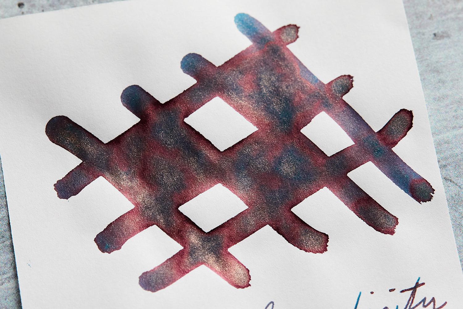 Close up of half-colored checkerboard doodle made with Diamine Serendipity fountain pen ink on white background