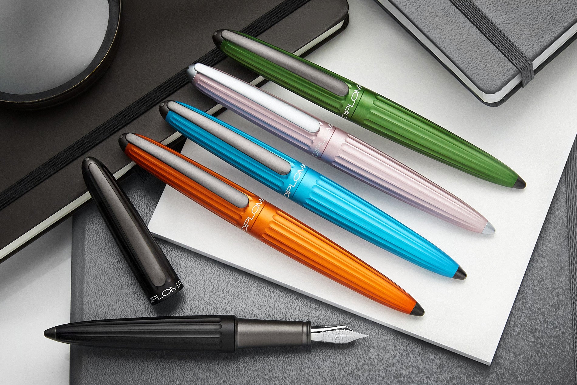 Five colorful aluminum Diplomat Aero fountain pens on a desk