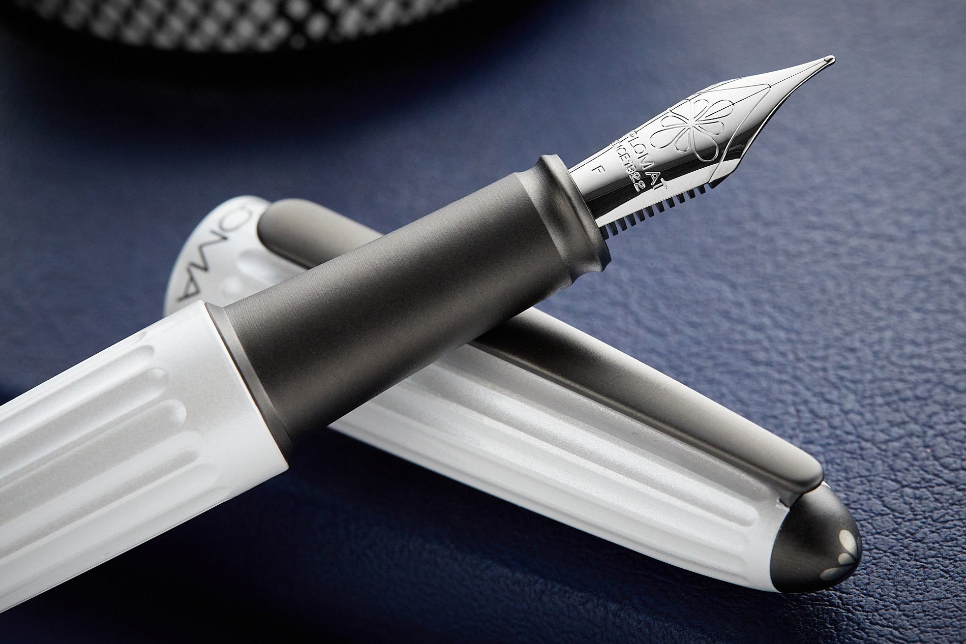 Diplomat Aero in Lacquered White pen resting on cap with dark blue background