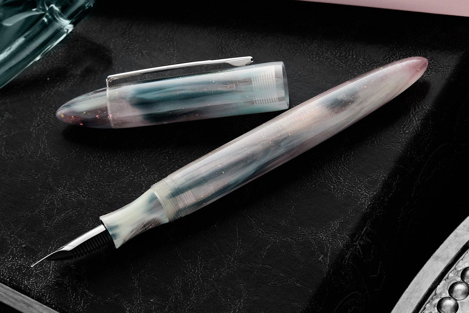 Edison foutnain pen in pale pink, blue, gray and glittery swirly resin, uncapped, on black background