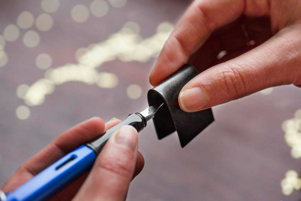 A hand using a rubber grip to remove a fountain pen's nib