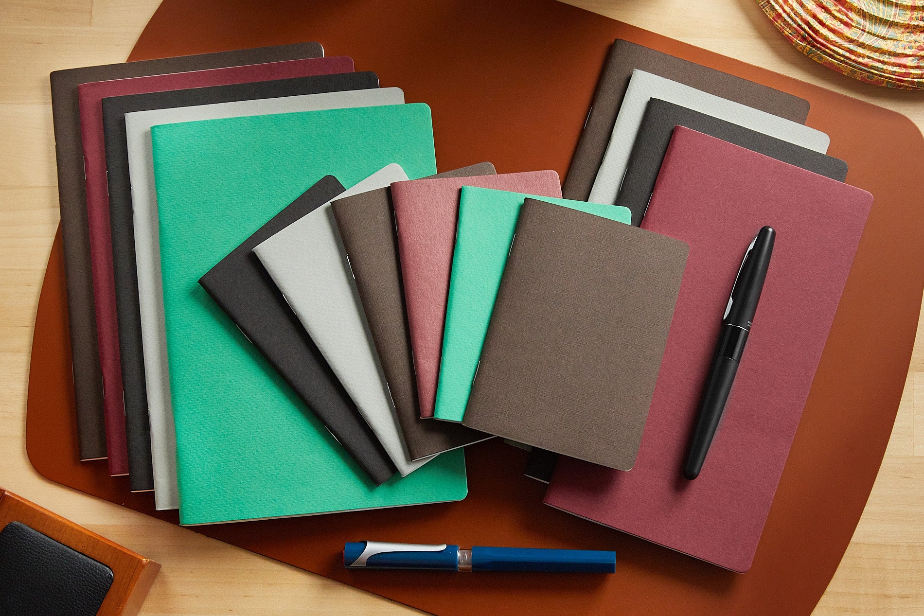 A variety of Goulet Notebooks, stacked and closed, on a desk