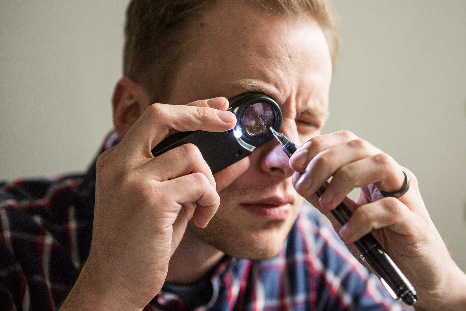 Drew Brown using a loupe to inspect a fountain pen nib