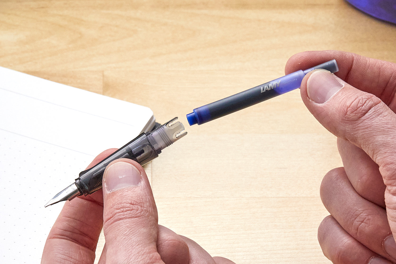 Holding a blue LAMY ink cartridge, about to install into a pen