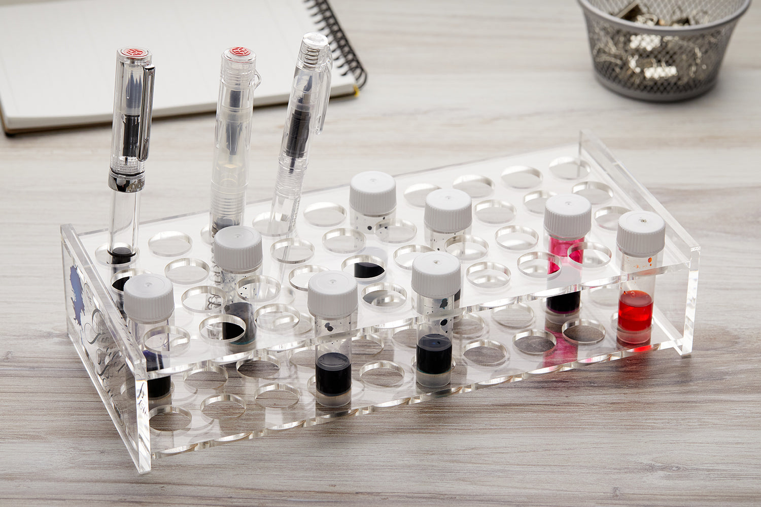 Clear acrylic ink sample vial holder with random ink samples and fountain pens