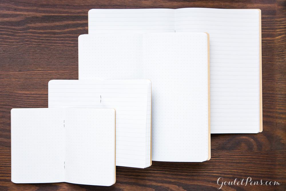 Four sizes of Goulet Notebooks, open on a wooden desk