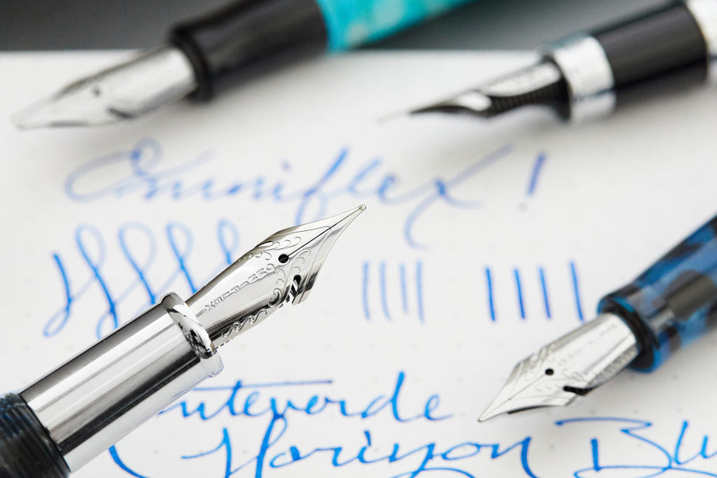 Close up of the Omniflex nib on a fountain pen with writing in the background