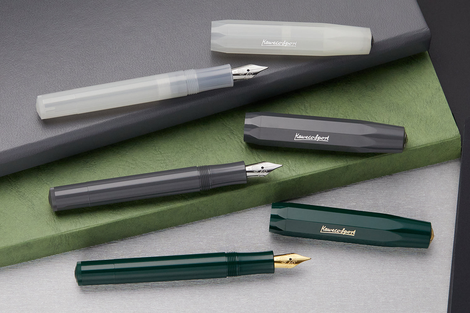 Three Kaweco Sport fountain pens in clear, grey, and green