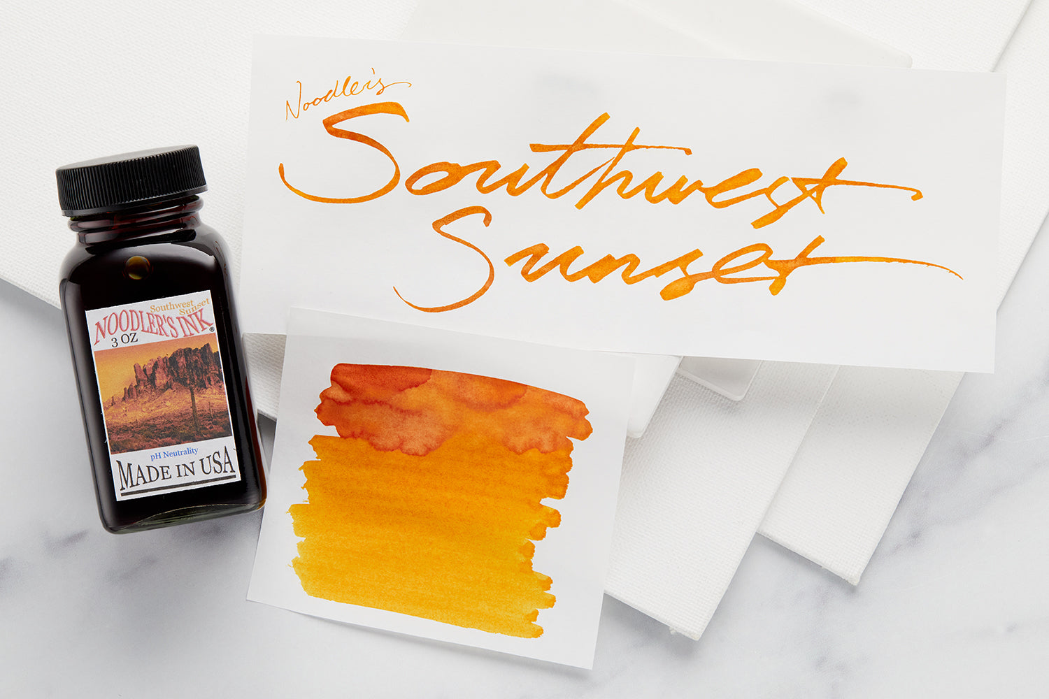 Bottle of Noodler's Southwest Sunset with swab and writing sample on white background