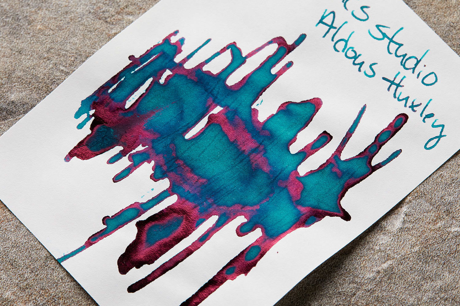 Organics Studio Aldous Huxley ink splatter and bottle on desk background