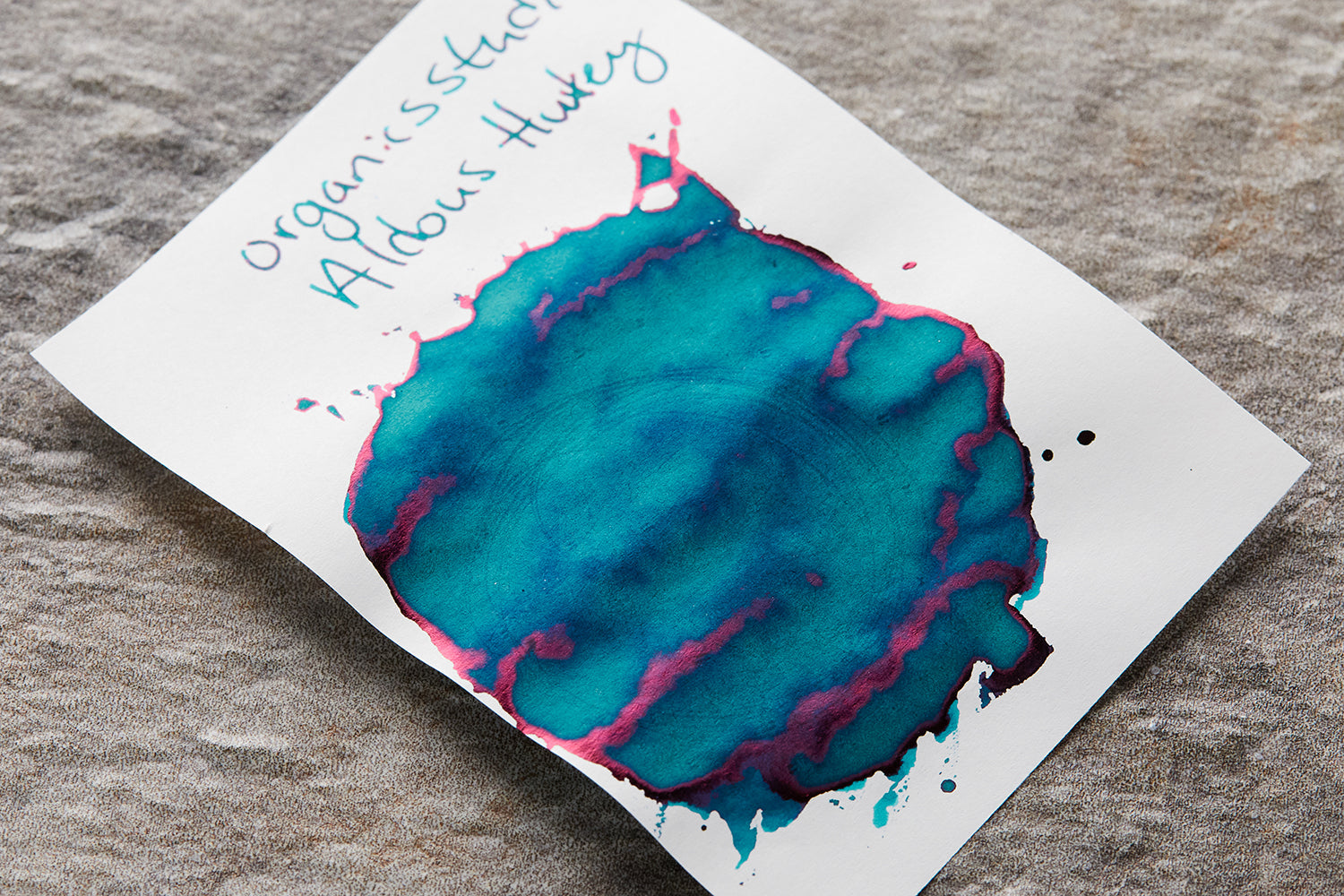 Organics Studio Aldous Huxley ink splatter and bottle on desk background