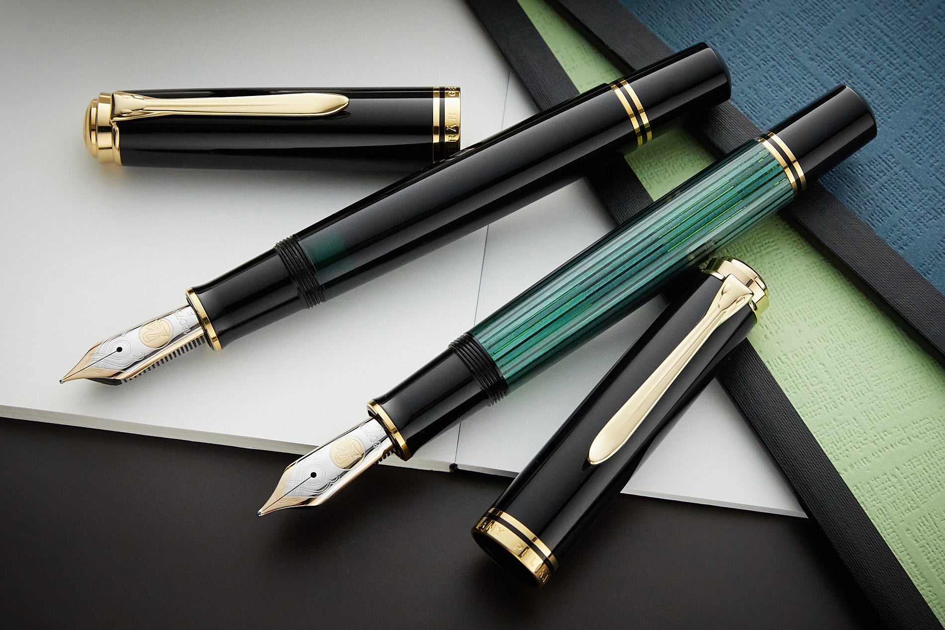 two Pelikan M1000 fountain pens, one in black and one in green