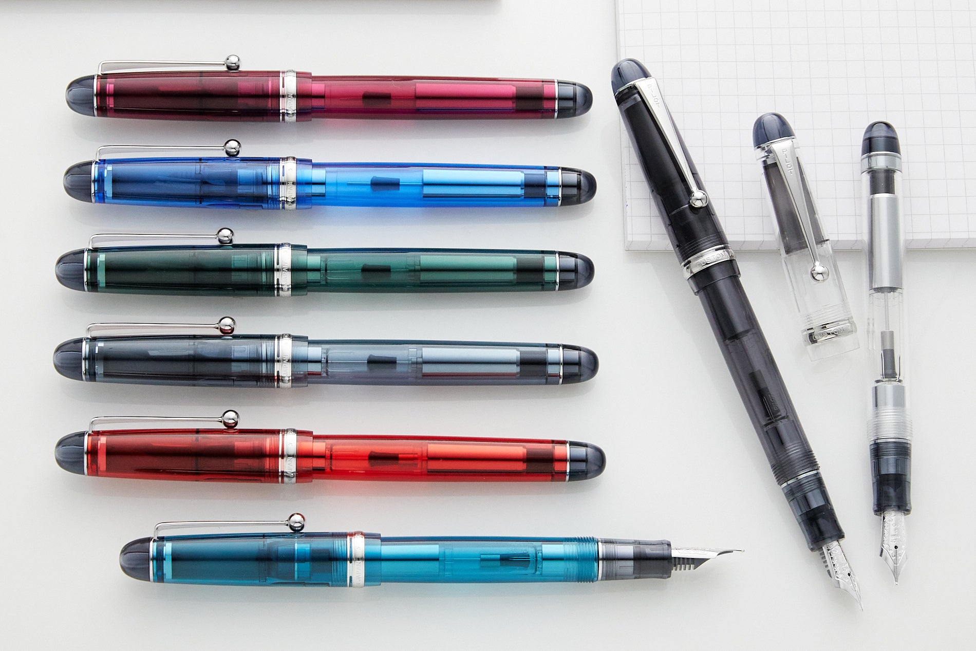 Colorful fountain pens lined up on a white background