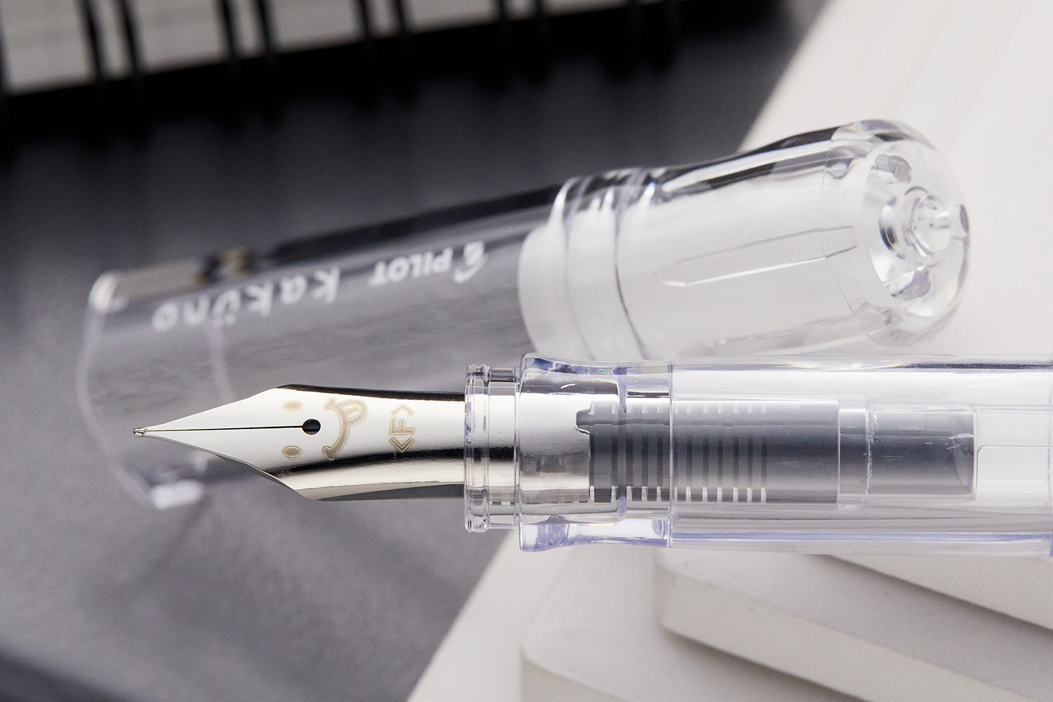 Clear fountain pen with a steel nib with a winking smiley face on it
