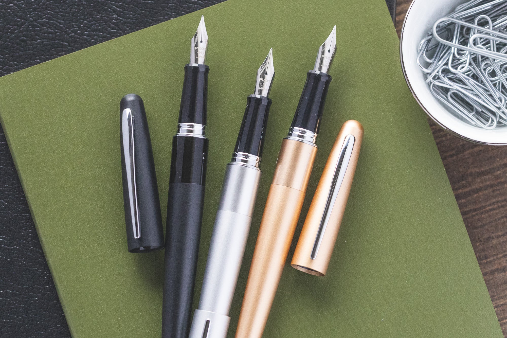 Black, Silver and Sold Pilot Metropolitans uncapped on a green notebook