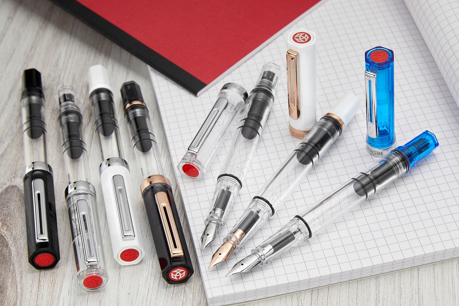 A group of fountain pens with a clear barrel, some capped and some uncapped