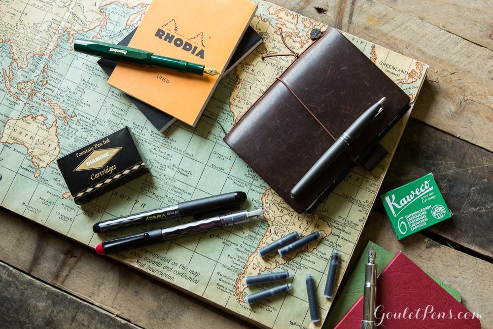 Assorted fountain pens and notebooks on a map