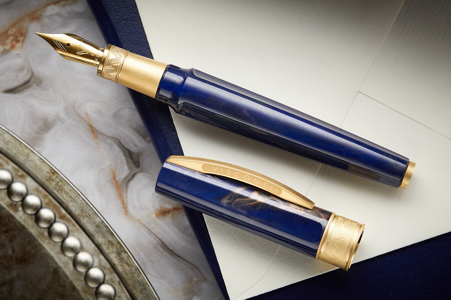 Visconti Mirage Mythos fountain pen in blue on white paper on top of a marble background