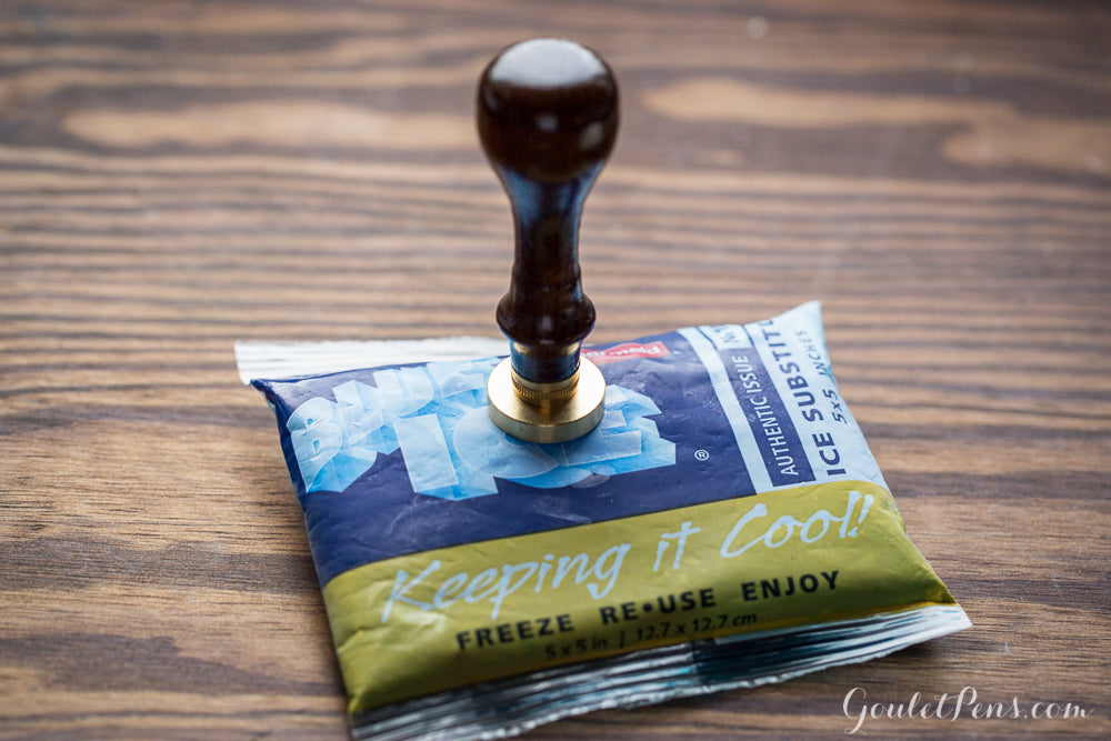 A wax seal with wooden handle resting on an ice pack