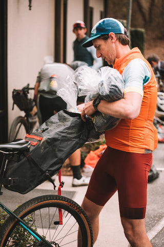 a cyclist loads bags of custom socks into his bike storage